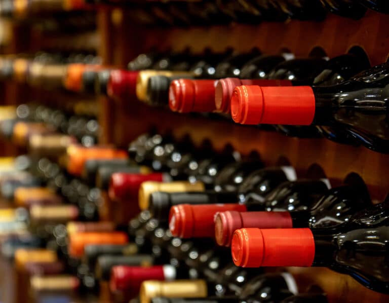 Serving and storing wine - bottles of black red wine lined up and stacked on wooden wine rack shelves