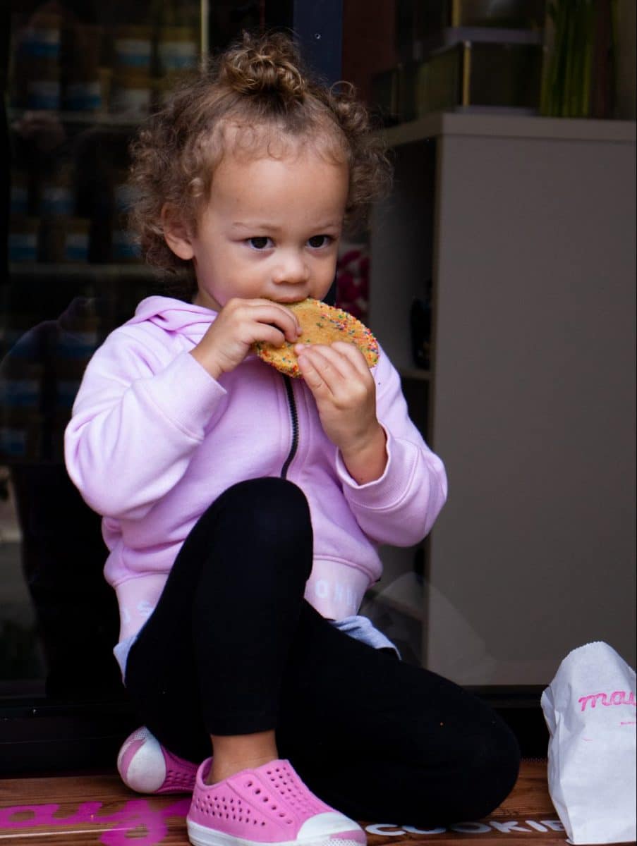 Little girl eating a cookie from Maya's Cookies
