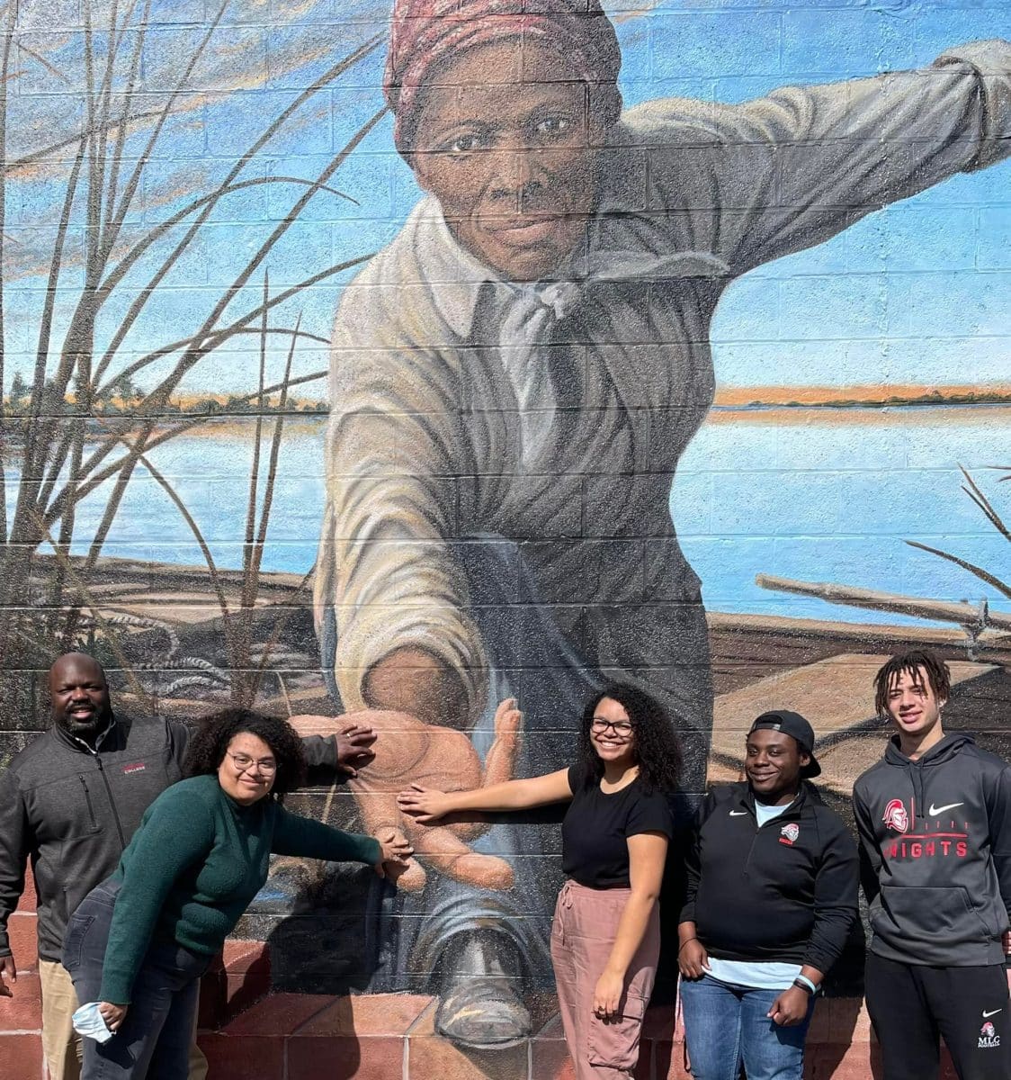 Professor with daughters and students in front of the Harriet Tubman “Take My Hand” mural located on the side of the museum