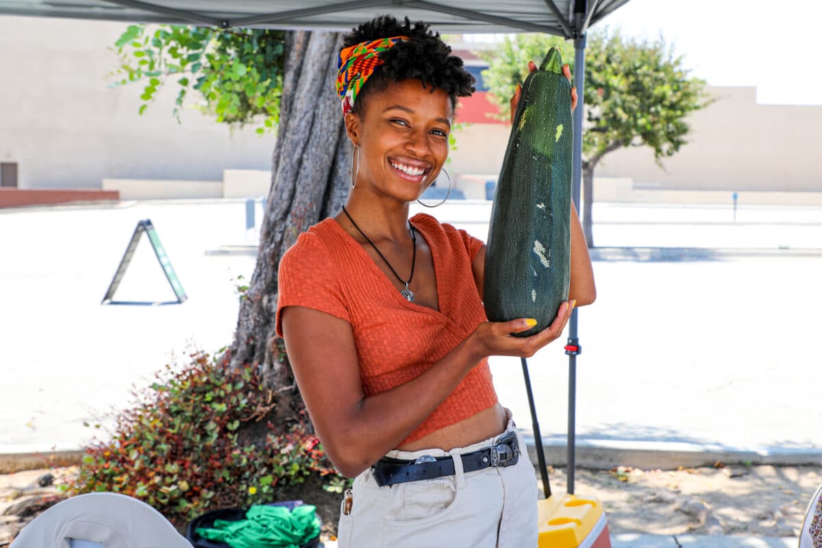 Prosperity Market vendor holding up giant zucchini