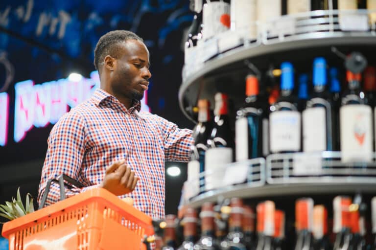 African American man in grocery store buying wine