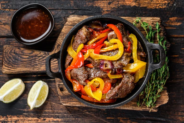 Fajitas beef meat traditional Mexican food dish in a pan. Dark wooden background. Top view.